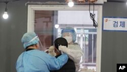 12일 한국 서울의 신종 코로나바이러스 검사소에서 의료진이 검체를 채취하고 있다.