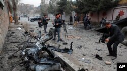 FILE - Afghan journalists film at the site of a bombing attack in Kabul, Afghanistan, Feb. 20, 2021. 