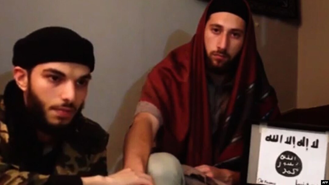 An image grab taken from a video released July 27, 2016, by Amaq News Agency, an online service affiliated with the Islamic State (IS) group, purportedly shows the two men who stormed into a church in the northern French town of Saint-Etienne-du-Rouvray and cut the throat of a 86-year-old priest at the altar, identifying themselves as Abu Jaleel al-Hanafi (L) and Ibn Omar (R) sitting next to the logo of the IS group while pledging allegiance to IS leader Abu Bakr al-Baghdadi. 