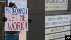 Furloughed EPA worker Jeff Herrema holds a sign outside the offices of U.S. Senator Mitch McConnell, in Park Hills, Kentucky, Jan 22, 2019.