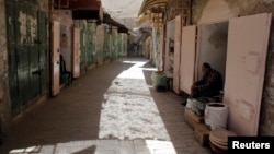 FILE - A Palestinian shop owner waits for customers at his shop in a market in the Old City of the West Bank town of Hebron.