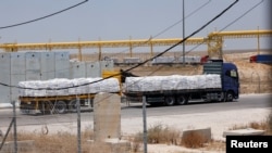 Truk-truk Mesir berisi bantuan kemanusiaan melaju di perlintasan Kerem Shalom di selatan Israel menuju Jalur Gaza di tengah konflik yang berlangsung antara Israel dan kelompok Hamas Palestina, Kamis, 30 Mei 2024. (Foto: Amir Cohen/Reuters) 