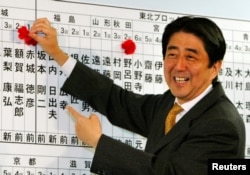 Shinzo Abe, sekretaris jenderal Partai Demokrat Liberal (LDP) yang berkuasa, membubuhkan bunga pada nama calon LDP, saat ia memeriksa kemajuan penghitungan suara di markas LDP di Tokyo 9 November 2003.(Foto: REUTERS/Kimimasa Mayama)