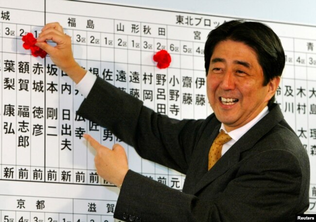 Shinzo Abe, sekretaris jenderal Partai Demokrat Liberal (LDP) yang berkuasa, membubuhkan bunga pada nama calon LDP, saat ia memeriksa kemajuan penghitungan suara di markas LDP di Tokyo 9 November 2003.(Foto: REUTERS/Kimimasa Mayama)