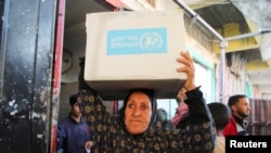 Seorang warga Palestina membawa kardus berisi bantuan yang dibagikan oleh UNRWA di Khan Younis, di selatan Jalur Gaza, pada 21 Januari 2025. (Foto: Reuters/Hatem Khaled)