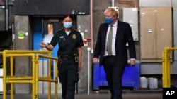 Britain's Prime Minister Boris Johnson, wearing a face mask, talks with paramedic Cindy Fu during a visit to the headquarters of the London Ambulance Service NHS Trust, July 13, 2020.