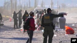 ARCHIVO - Un migrante es dirigido por un miembro de la Oficina de Aduanas y Protección Fronteriza de EEUU mientras cientos de migrantes se reúnen a lo largo de la frontera el martes 5 de diciembre de 2023 en Lukeville, Arizona.