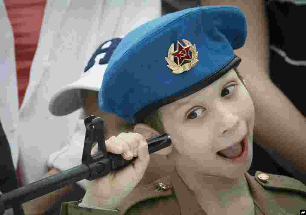 A boy plays with a machine gun at a weapon exhibition, during celebrations for Navy Day in St.Petersburg, Russia.