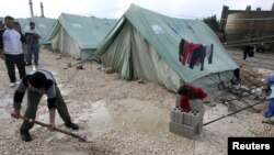 Syrian refugees shovel away water pooled outside their tents after heavy rain, at a center funded by the International Islamic Relief Organization of Saudi Arabia (IIROSA), which provides shelter for Syrian refugees in al-Marj, in the Bekaa valley, Lebanon, January 7, 2013.