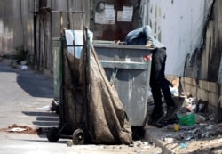 FILE - A man searches through a garbage bin in Beirut, Lebanon, June 30, 2020.