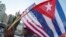 A man waves the US and Cuban flags as he walks in front of the new Cuban Embassy shortly before it's official ceremonial opening July 20, 2015, in Washington, D.C. 