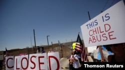 FILE - Activists hold a protest against the treatment and conditions of children in immigration detention outside U.S. Customs and Border Protection's Border Patrol station facilities in Clint, Texas, June 27, 2019.