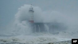 Waves crash over the harbor and a lighthouse, as Storm Ciara hits Newhaven, on the south coast of England, Feb. 9, 2020. 
