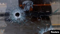 Impactos de bala se observan en la ventana de una pizzería donde desconocidos armados mataron a cuatro empleados de una emisora radial en Ciudad Juárez, México, el 11 de agosto de 2022. Foto Reuters.