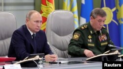 FILE - Russia's President Vladimir Putin visits the National Defence Control Center (NDCC), with Chief of the General Staff of Russian Armed Forces Valery Gerasimov seen nearby, in Moscow, Dec. 16, 2018.