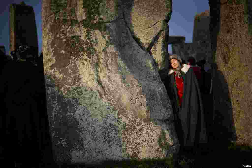 A person rests on the Stonehenge stone circle, as they welcome in the winter solstice, as the sun rises in Amesbury, Britain.