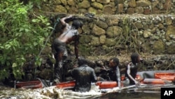 En esta foto tomada el 7 de febrero de 2012, trabajadores intentan contener un derrame de petróleo en el río Guarapiche, en las afueras de Maturin, Venezuela.