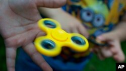 FILE - A boy plays with a fidget spinner in Moscow, Russia, July 19, 2017. (AP Photo/Ivan Sekretarev)