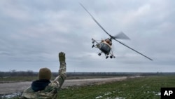 Ukrajinski vojnik maše posadi vojnog helikoptera koi se vraća iz borbene misije, blizu linije fronta u oblasti Hersona, Ukrajina, 8. januara 2023.