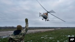 A Ukrainian soldier waves to a military helicopter returning from the combat, close to the frontline in the Kherson region, Ukraine, Jan. 8, 2023. 