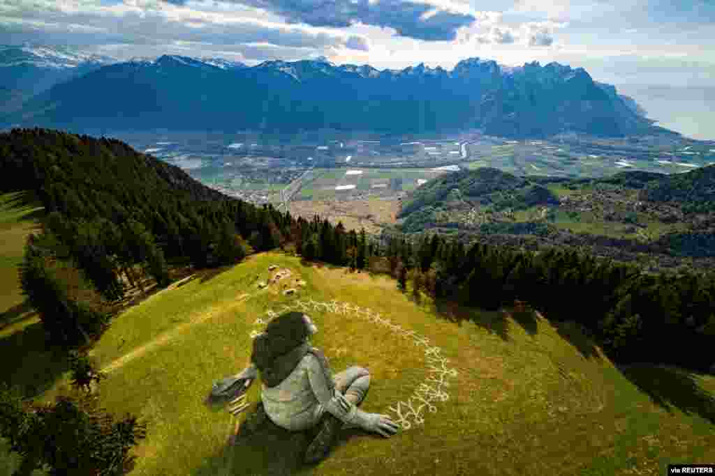 An artwork called "Beyond Crisis" by French artist Guillaume Legros aka Saype and created with an eco paint made out of chalk and coal over a 3000 sqm field is pictured in Leysin, Switzerland. (Valentin Flauraud/SAYPE/Handout)
