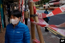 A woman wearing face mask walks on a street in Hong Kong, Feb. 18, 2020. COVID-19 viral illness has sickened millions of people in China since December.
