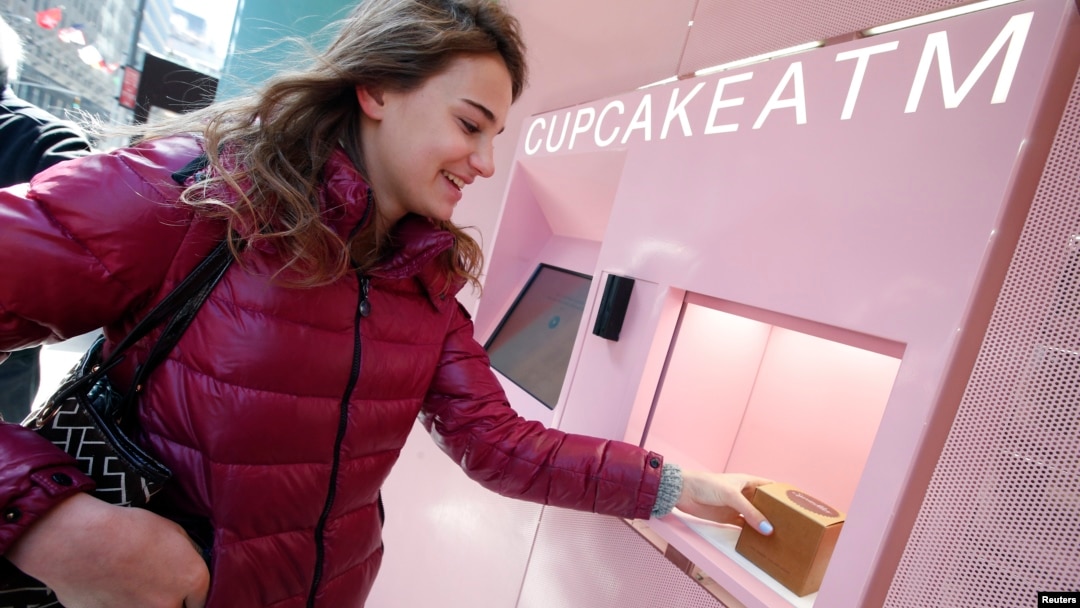 Seorang perempuan mengambil cupcake marshmallow coklat dari Cupcake ATM di Sprinkles Cupcake Bakery di Manhattan, New York City (26/3). (Reuters/Mike Segar)