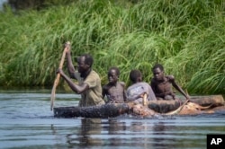 FILE - A father and his sons transport cows from a flooded area to drier ground using a dugout canoe, in Old Fangak county, Jonglei state, South Sudan on Nov. 25, 2020. (AP Photo/Maura Ajak, File)