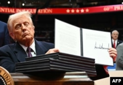 Američki predsednik Donald Tramp držiu uredbu koju je upravo potpisao tokom inauguracione parade u Kapital 1 areni, u Vašingtonu, 20. januara 2025. (Foto: Jim VATSON / AFP)