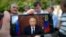 People stand in a street in Moscow, Russia, Aug. 29, 2018, with some using their smart phones to watch a televised address by Russian President Vladimir Putin.