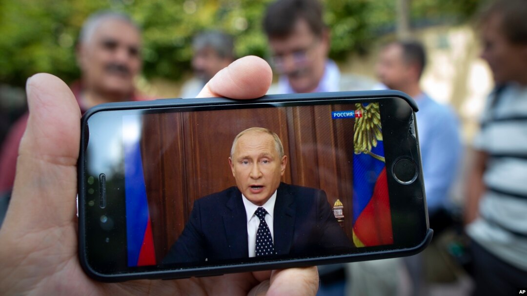 Arhiva - Ljudi na ulici preko telefona prate televizijsko obraćanje predsednika Rusije Vladimira Putina povodom najavljene penzione reforme, u Moksvi, 29. avgusta 2018.