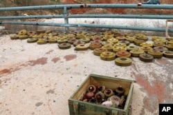 FILE - In this photo released by the Syrian official news agency SANA, landmines are collected by Syrian engineering troops from the M5 highway, recaptured by President Bashar Assad's forces this week, in Aleppo, Syria, Feb. 15, 2020.