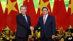 Perdana Menteri Tiongkok Li Qiang, kiri, dan Perdana Menteri Vietnam Pham Minh Chinh berjabat tangan sebelum pertemuan di Hanoi, 13 Oktober 2024. (Duong Van Giang/VNA via AP)