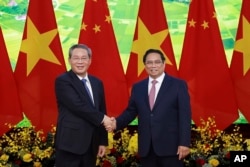 Chinese Premier Li Qiang, left, and Vietnamese Prime Minister Pham Minh Chinh shake hands before a meeting in Hanoi, Oct. 13, 2024. (Duong Van Giang/VNA via AP)