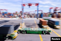Autonomous electric vehicles carry shipping containers at the Long Beach Container Terminal (LBCT) in Long Beach, California, U.S., April 20, 2023. (REUTERS/Mike Blake)