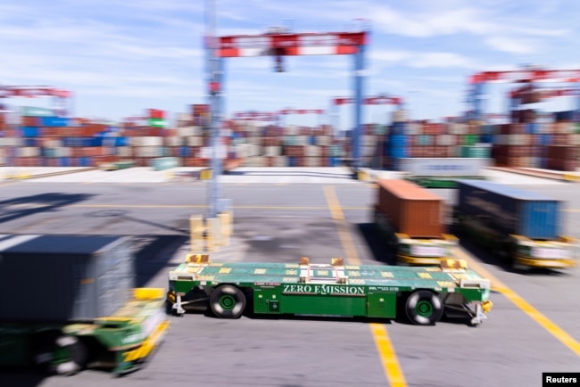 Autonomous electric vehicles carry shipping containers at the Long Beach Container Terminal (LBCT) in Long Beach, California, U.S., April 20, 2023. (REUTERS/Mike Blake)