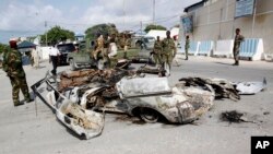 FILE - Somali soldiers stand near the wreckage of car bomb that was detonated at the main gate of the presidential palace in Mogadishu, July, 9, 2014.
