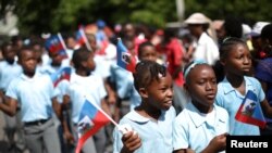 Yon ti fi ki kenbe yon drapo aysiyen nan men li pandan dewoulman selebrasyon fèt drapo aann Ayiti. Foto REUTERS/Andres Martinez Casares 