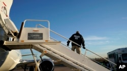 FILE - An Immigration and Customs Enforcement (ICE) officer awaits individuals to board a deporartion flight, in Houston, Texas, Nov. 16, 2018.