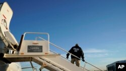 FILE - An Immigration and Customs Enforcement (ICE) officer awaits individuals to board a deporartion flight, in Houston, Texas, Nov. 16, 2018.