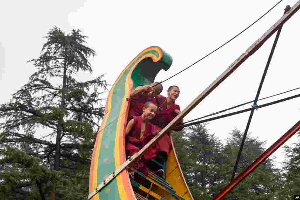 Novice Buddhist monks react as they ride a pendulum swing at a local fair in Dharmsala, India.
