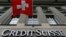 Logo bank milik Swiss, Credit Suisse, tampak di bawah bendera Swiss di sebuah gedung yang terletak di Federal Square di Bern, 15 May 2014 (foto: Reuters/Ruben Sprich)