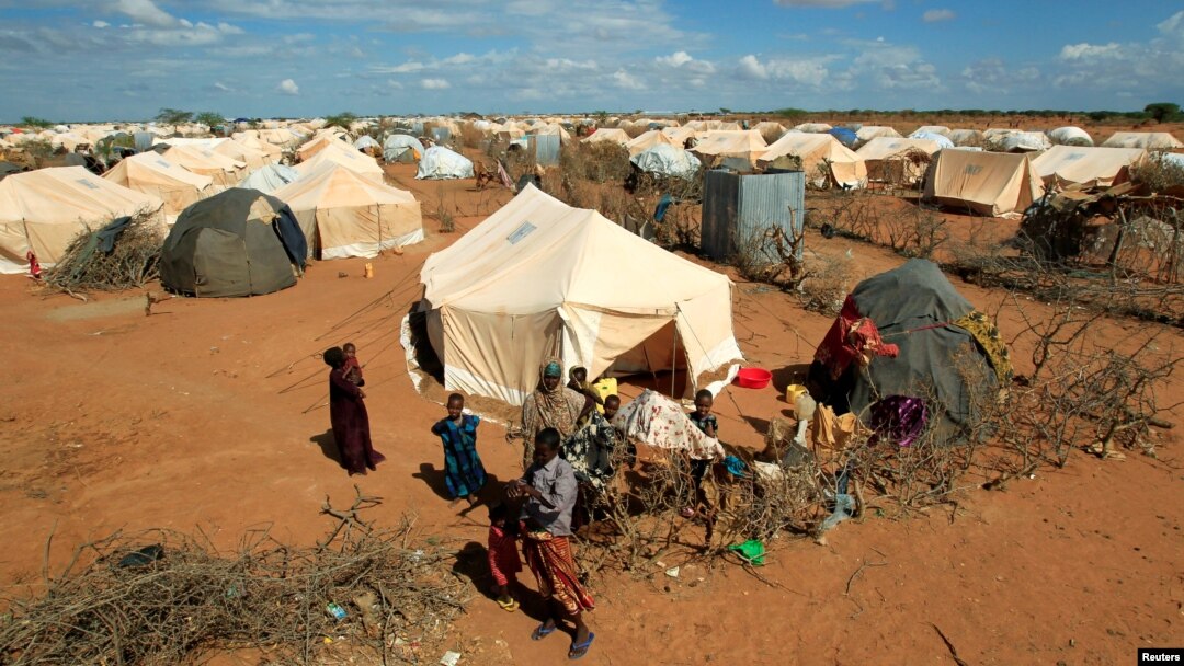 FILE - Refugees stand outside their tent at the Ifo Extension refugee camp in Dadaab, near the Kenya-Somalia border, Oct. 19, 2011.