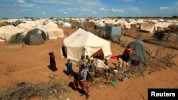 FILE - Refugees stand outside their tent at the Ifo Extension refugee camp in Dadaab, near the Kenya-Somalia border, Oct. 19, 2011.