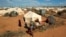 FILE - Refugees stand outside their tent at the Ifo Extension refugee camp in Dadaab, near the Kenya-Somalia border, Oct. 19, 2011.