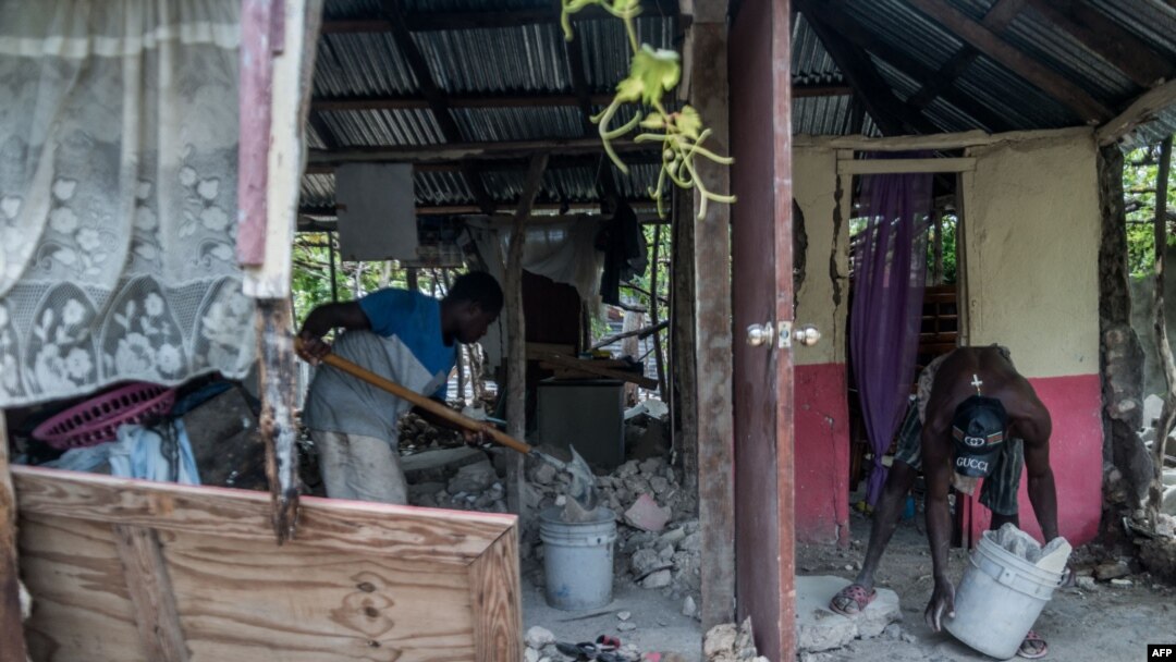 Dos jóvenes limpian una casa gravemente dañada por el terremoto en Chardonnieres, Haití el 18 de agosto de 2021.