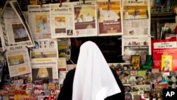 A nun looks at front pages showing newly elected Pope Francis at a newsstand near the Vatican, March 14, 2013.