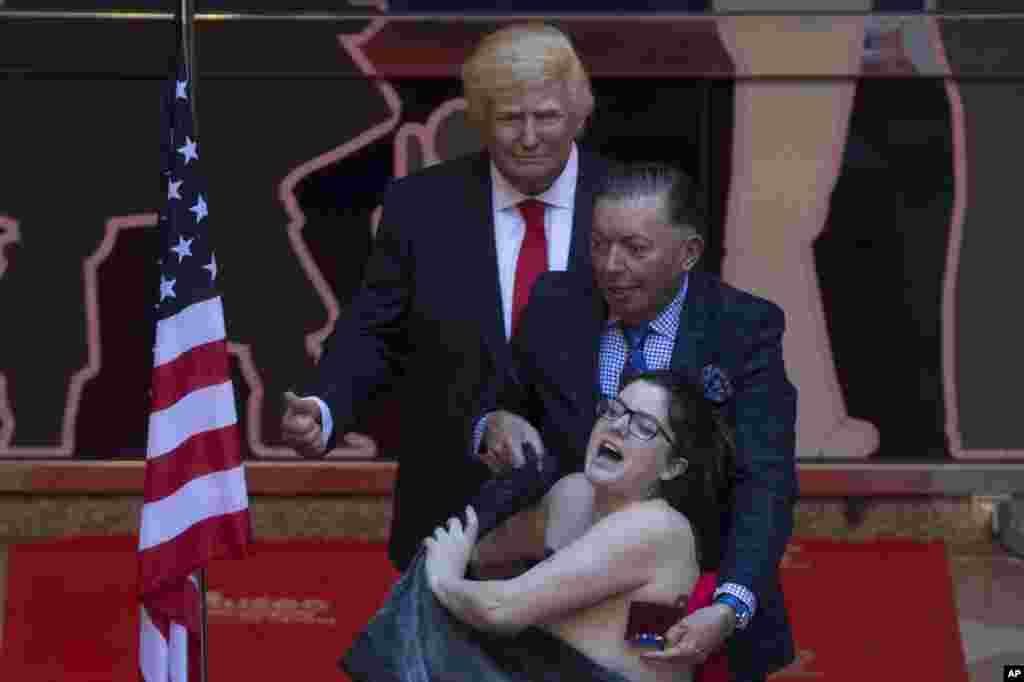 A woman makes a semi-naked protest during the inauguration of a figure of U.S. President-elect Donald Trump at the Wax museum in Madrid, Spain.