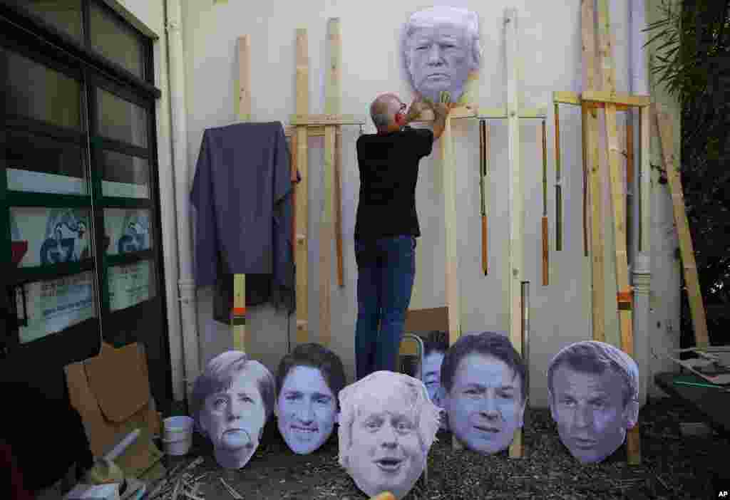 A man fixes an image of President Donald Trump to a wooden pole as he prepares for an anti-G-7 demonstration at a camp near Hendaye, France. 