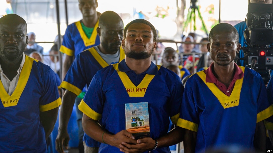 FILE - Marcel Malanga holds the Bible as he attends a trial where he is accused with others of a failed coup attempt, at Kinshasa's Ndolo prison in Kinshasa on Sept. 13, 2024.